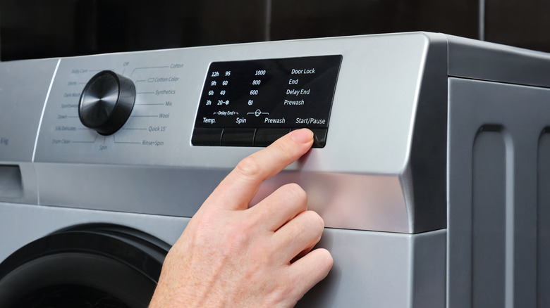 Man changing the settings on modern washing machine control panel