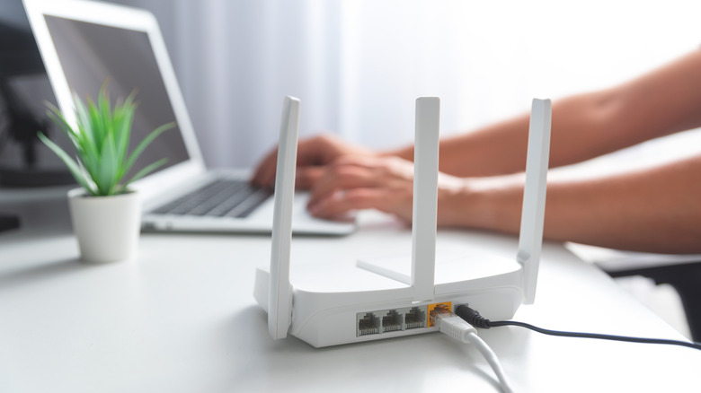 A Wi-Fi router next to a person working on a laptop