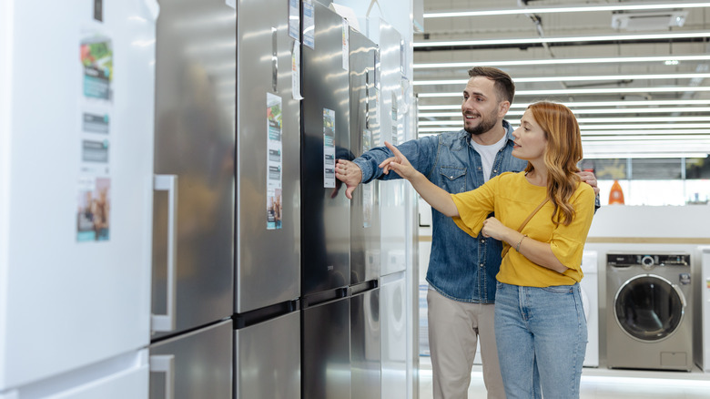 Couple looking at brand new refrigerators in appliance store