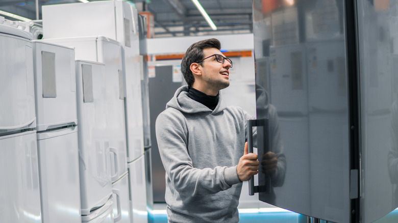 Young man inspecting refrigerator at appliance store