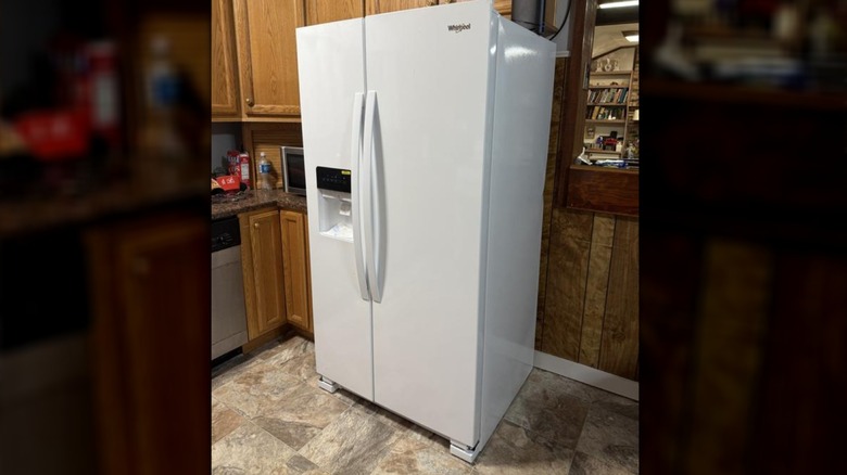 White Amana fridge in traditional wood kitchen with tile floor and paneled walls