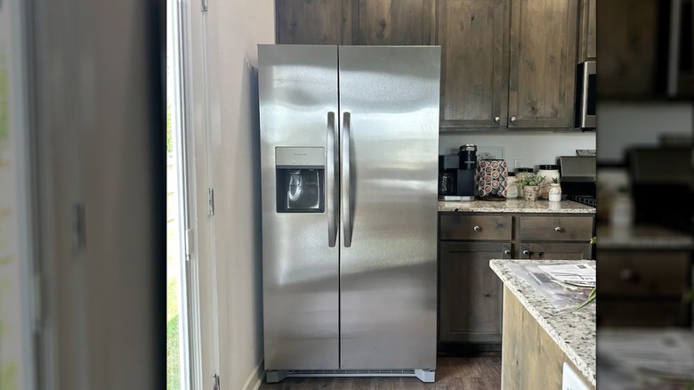 Stainless steel Frigidaire fridge in rustic stylish kitchen with weathered cabinets