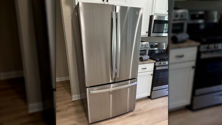 Stainless steel GE refrigerator in classic white and granite laminate kitchen