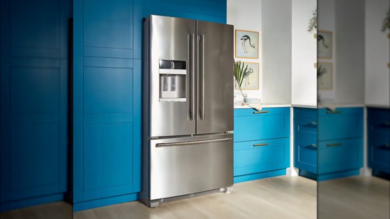 Stainless steel Maytag refrigerator in unique blue cabinet kitchen