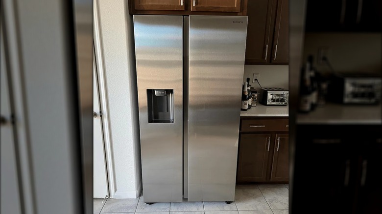 Samsung refrigerator beside dark wood cabinets and white countertops