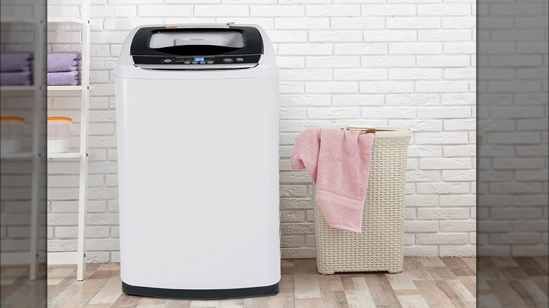 Portable Black + Decker washer in laundry room with white brick wall