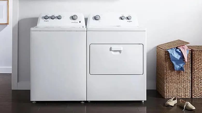 Whirlpool washer and dryer set beside overflowing laundry basket