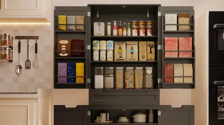 The doors of a black kitchen pantry unit are opened to reveal neatly organized kitchen staples