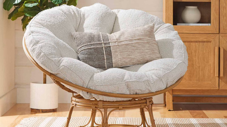 A potted fiddle leaf fig sits behind a papasan chair