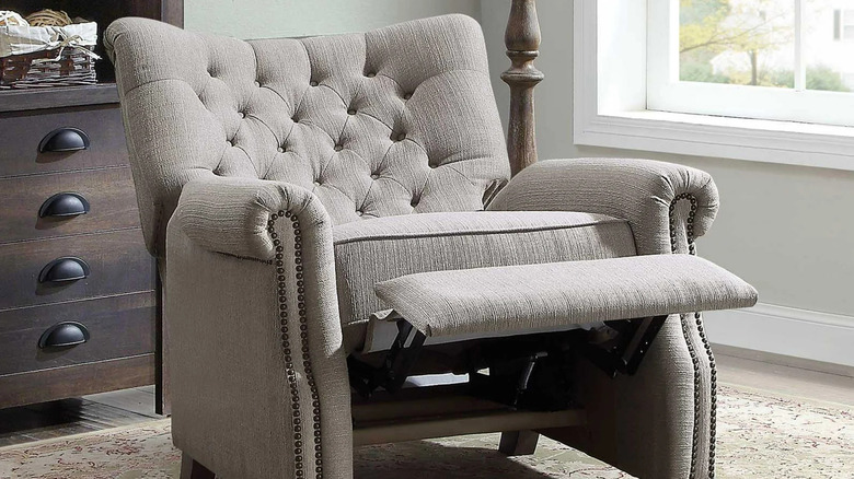 A tufted gray recliner is shown in a home library
