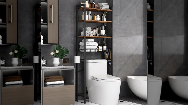Towels and toiletries are neatly styled on a black and wood over the toilet storage shelf
