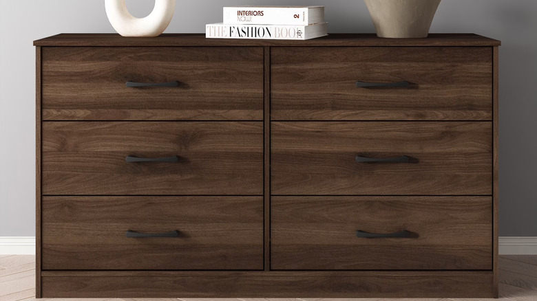 Two large coffee table books sit on top of a walnut-colored dresser