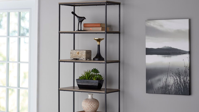 A black and wood Mainstays bookshelf is styled with neutral decor
