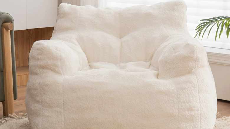A white beanbag chair sits in front of a bright window