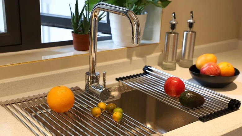 Two Ahyuan Foldable Stainless Dish Drying Racks hold vegetables over a stainless steel sink