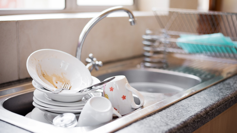 A kitchen sink is full of dirty dishes