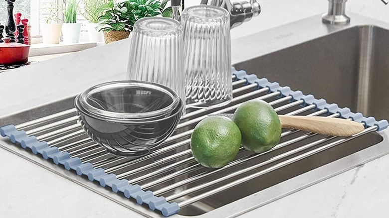 Glasses, a bowl, and limes sit on a Seropy Kitchen Foldable Stainless Rollup Dish Drying Rack
