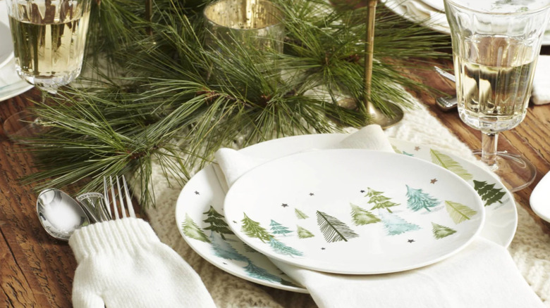 Two plates featuring green and blue trees and gold stars on a decorated festive table.