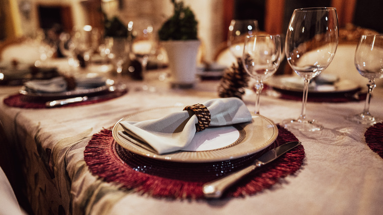 A napkin lays on top of a plate on a table set for a festive dinner.