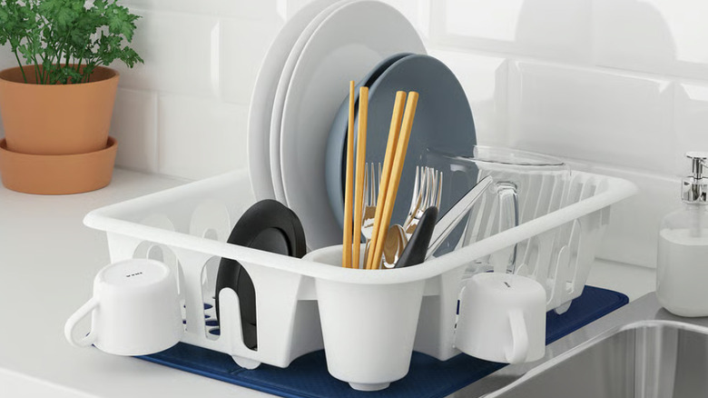 Fully stocked white IKEA dish raack on blue drying mat in white kitchen