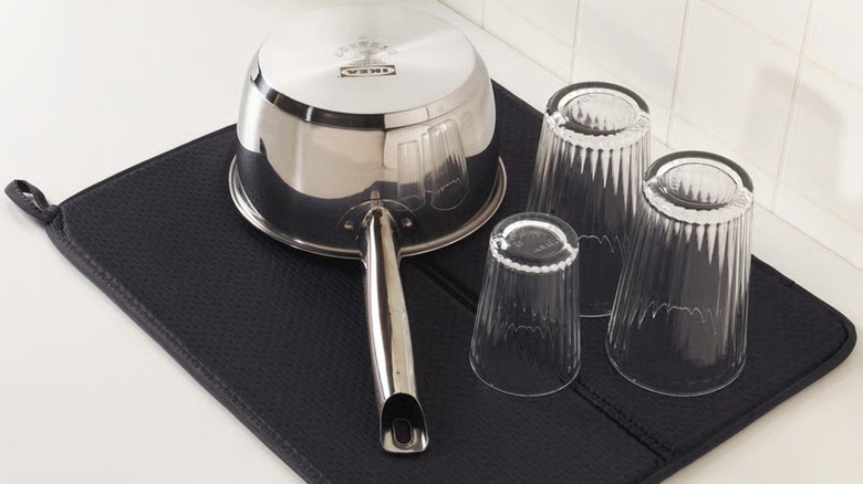 Plush dark IKEA dish mat with stainless steel cooking pan and glass cups drying on top