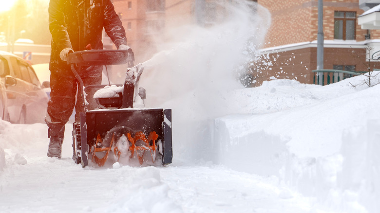 Person clearing sidewalk with snow blower
