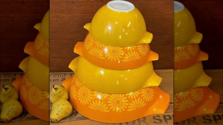 A set of orange and yellow Pyrex mixing bowls stacked upside down on top of each other.