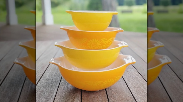 Orange and yellow Pyrex daisy mixing bowl set stacked together for display.