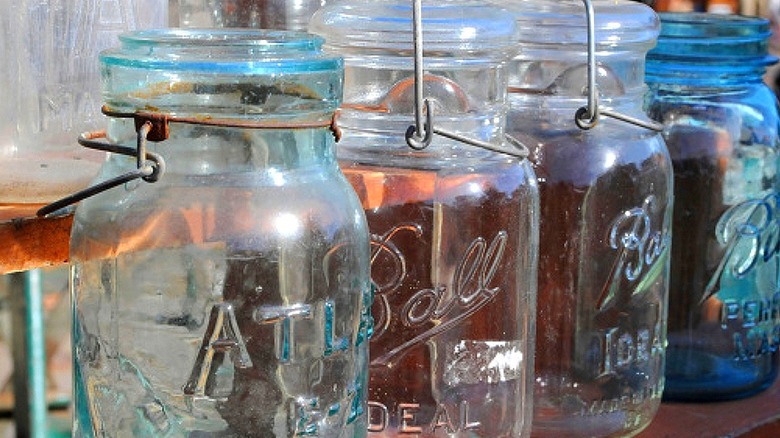 A vintage Atlas jar with three Ball jars sitting together on a shelf