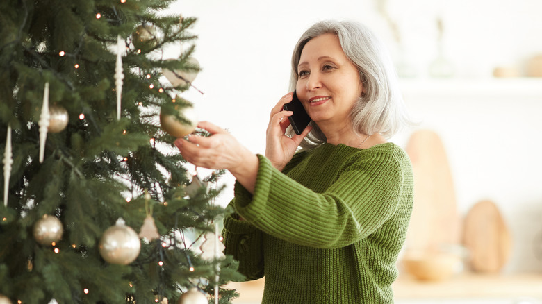 Woman on phone touching tree