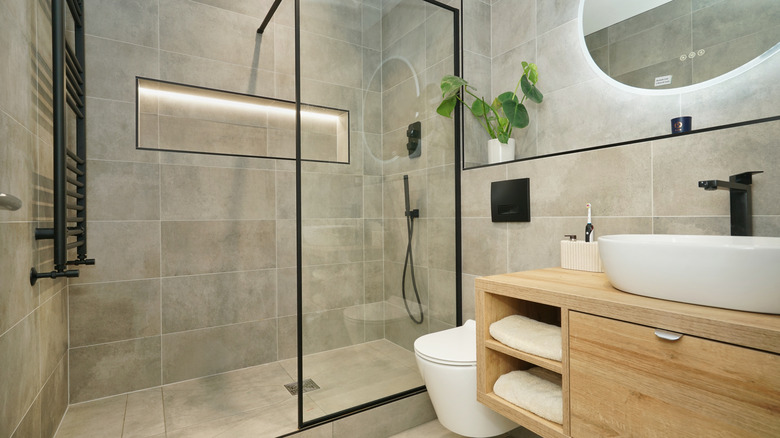 A modern glass shower with an opening on the opposite side of the shower from the knobs
