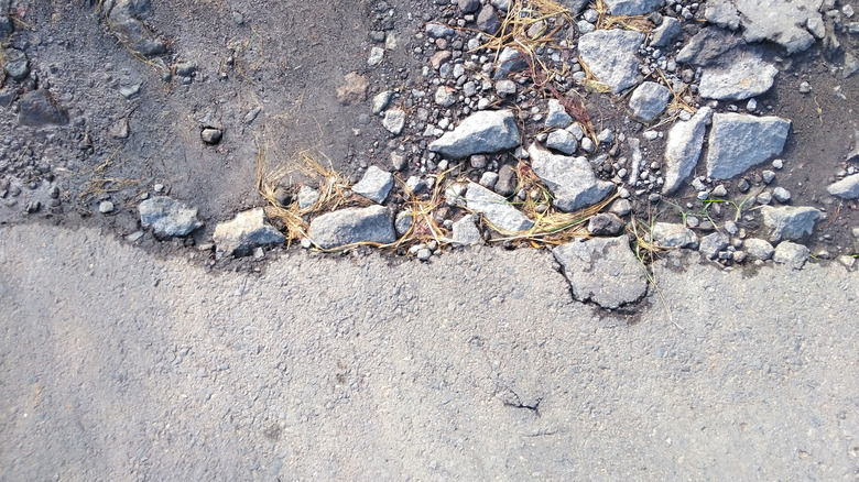 broken asphalt showing clay soil underneath