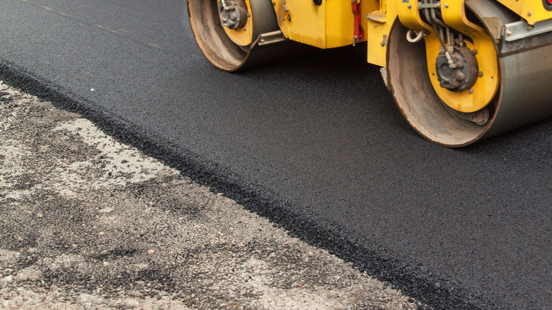 Roller vehicle tamping down asphalt on driveway