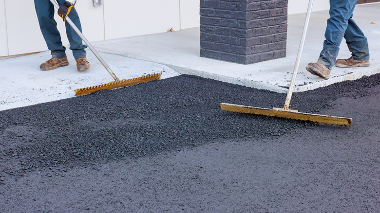 workers laying down an asphalt mix in a driveway
