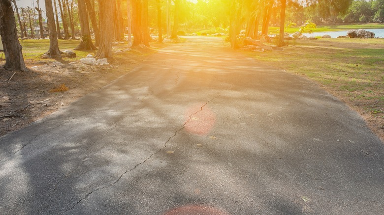 sun shining down on concrete road with cracks
