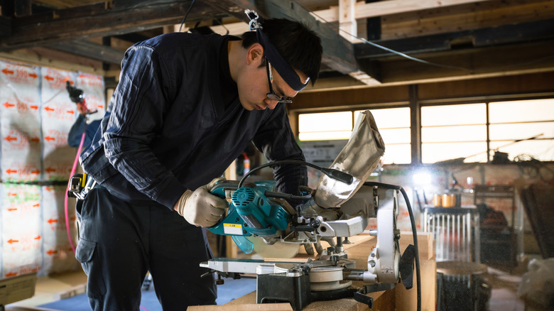 A home construction project features a man working on sawing pieces of wood.
