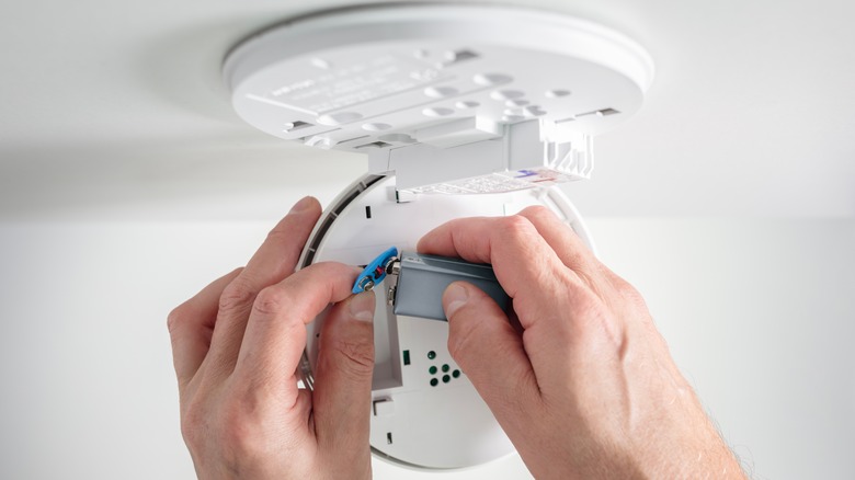 person changing the batteries in smoke detector
