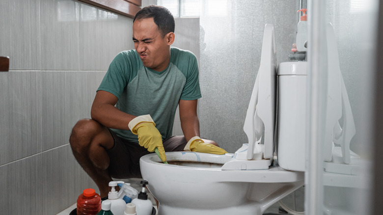 Man cleaning a stinky toilet