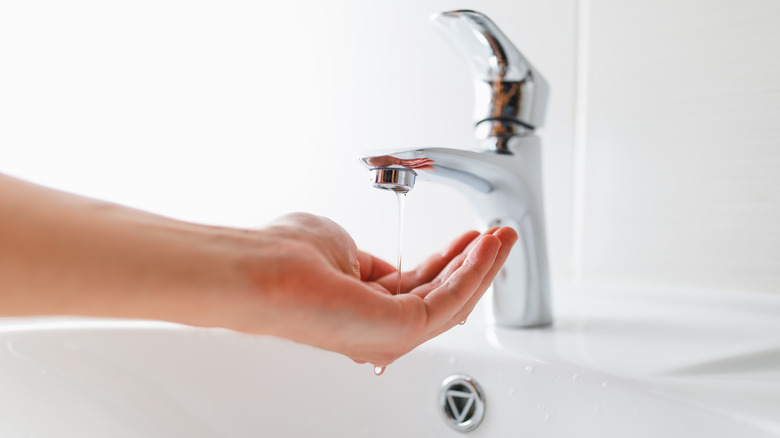 hand under low-pressure water stream