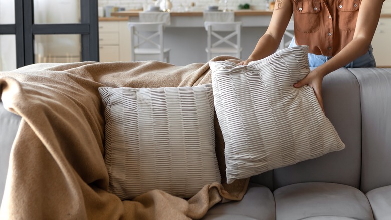 woman placing cushions on sofa 