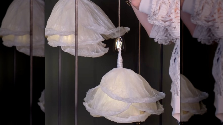 A light-skinned woman's hands hang flower pendant lamps