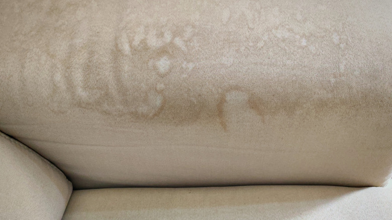 Stains and discoloration on the upholstery of a beige sofa