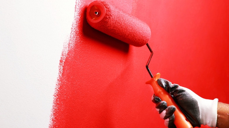 A hand with a red paint roller