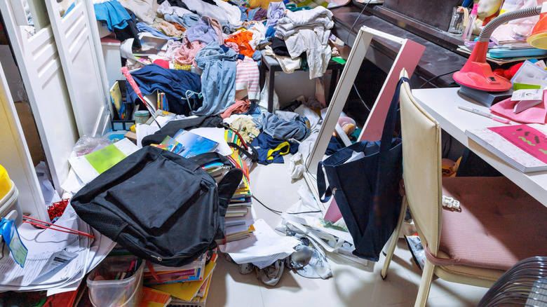 Cluttered room bedroom full of trash, clothes, and supplies