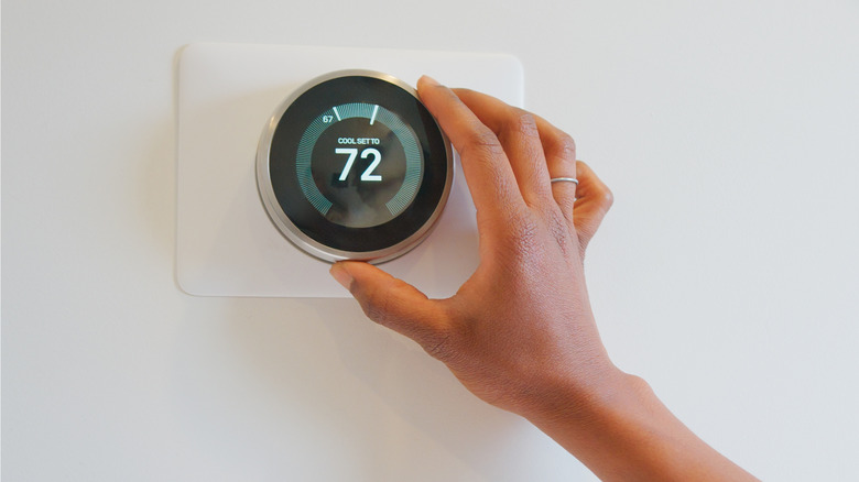 Hand setting up smart thermostat