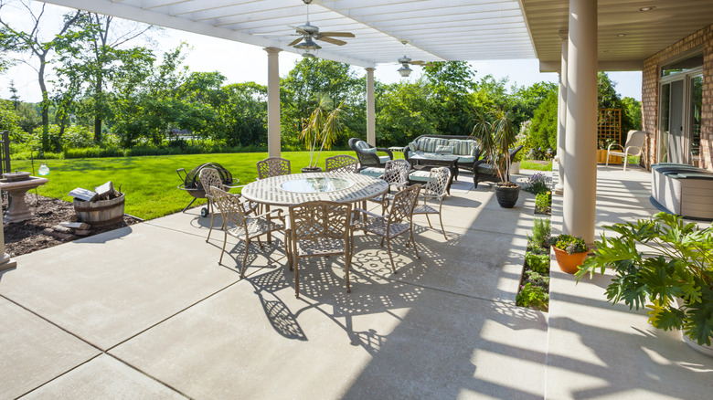Sunny patio with concrete floor by lawn.