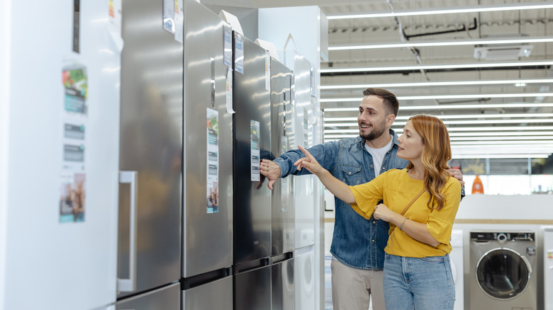 A couple looking at refrigerators at an appliance store