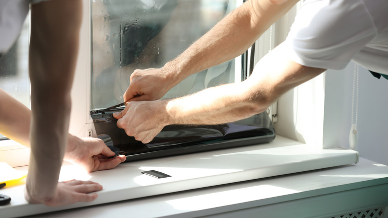 Two people applying tinted window film