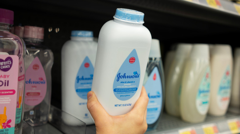 Close up of a person picking up bottle of baby powder from store shelf