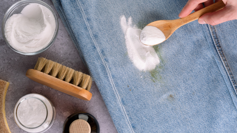 Close up of a person using baking soda to remove stain from jeans